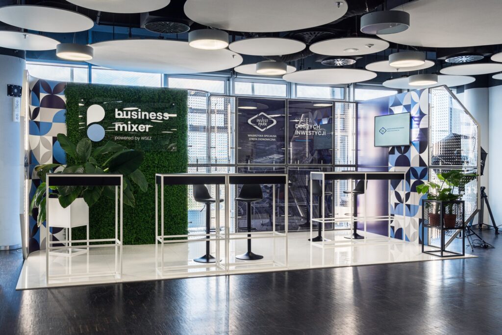 Stoisko targowe na konferencji Business Mixer - nowoczesna aranżacja z wykorzystaniem paneli graficznych i imitujących bukszpan